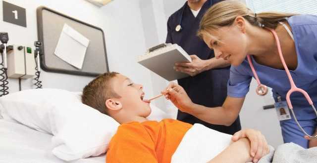 Female doctor examining boy (10-12) lying in hospital bed